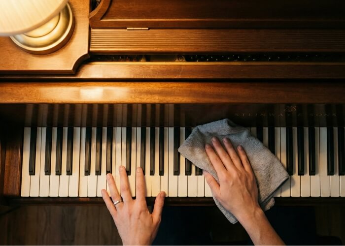 Someone carefully cleaning piano keys with a microfiber cloth as part of a daily instrument care routine.