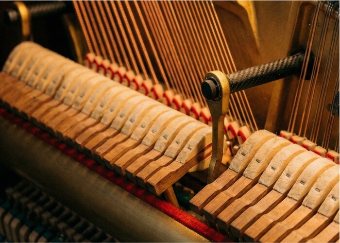 Modern upright piano action mechanism featuring advanced carbon-fiber components.