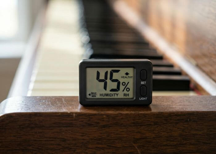 A digital hygrometer displaying safe moisture levels to prevent soundboard cracks.