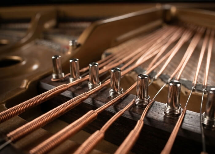 Close up of steel strings requiring professional piano servicing and tension adjustment.
